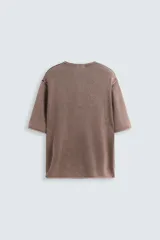 Camiseta relaxed fit de punto color marrón con efecto lavado, cuello redondo con cierre frontal de botonadura y manga corta.