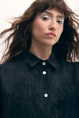 Vestido camisero color beige con estampado de líneas horizontales, con botones de nácar y sobrefalda integrada. Confeccionado en poliéster suave con leve rugosidad. Diseñado y confeccionado en Uruguay.