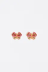Par de aros pequeños con forma de mariposa, hechos de metal dorado con detalles de esmalte rojo y rosa, y cristales verdes y blancos.