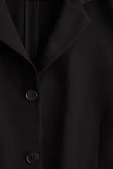 Blazer negro de punto pesado con solapas de muesca, corte entallado, hombreras, bolsillos delanteros ribeteados y abertura decorativa en los puños.