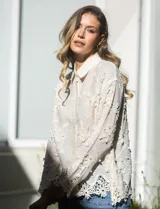 Camisa de algodón color crema, marca Liv Los Angeles, con bordado floral y terminaciones en crochet en puños y ruedo. Tiene cuello con solapa y abertura central con botones.