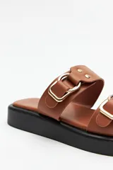 Sandalias marrones con plataforma baja y tiras anchas con hebillas metálicas.