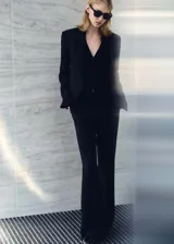 Pantalón de vestir negro de corte wide leg, con bolsillos laterales y cierre frontal con cremallera y botón.