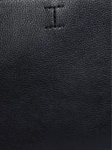 Cartera tote Calvin Klein negra de poliuretano con textura granulada. Tiene doble asa superior, cierre de cremallera y logo grabado en el frente.