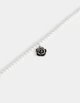 Collar corto de perlas sintéticas con dije de rosa metálica plateada y cierre de cinta de terciopelo negro.