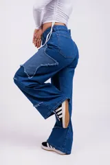 Pantalón de jean azul con parches en forma de estrella de un tono más claro y bordes desflecados.