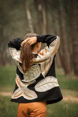 Cárdigan negro de lana con apliques de hojas en tonos beige, naranja y marrón.