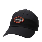 Gorro de tela negro, estilo gorra de béisbol, con visera curva y parche frontal bordado en naranja y blanco con el texto "THE ORIGINAL KRSTBLG EST. 1981".