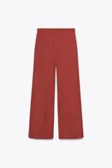 Pantalón color ladrillo de corte palazzo, con bolsillos laterales y traseros, detalle de pliegues en el frente y cierre frontal con cremallera, botón interior y gancho metálico. Confeccionado en hilatura con 21% de lino.