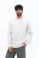 Remera de manga larga color negro, con escote redondo y un pequeño logo circular estampado en el pecho.