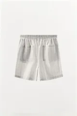 Shorts de algodón color gris claro con estampado de cuadros negros, tiro medio y cintura elástica.