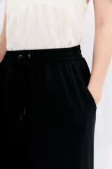 Pantalón crop negro de corte amplio, con cintura elástica ajustable con cordón y bolsillos laterales.