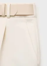 Pantalón de vestir color crema de corte palazzo, con pinzas en la cintura y cinturón fino con hebilla plateada.