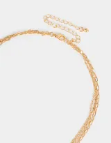 Collar corto dorado compuesto por tres cadenas de diferentes diseños: una de eslabones finos, una con perlas irregulares y otra de eslabones más grandes. Presenta dijes de frutas con strass de colores.