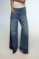 Pantalón de jean de tiro medio con cinco bolsillos, corte wide leg y detalle de tejido con lavado lateral combinado.