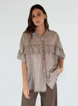 Camisa color amarillo con cuello clásico, cierre frontal con botones y mangas cortas con volados.