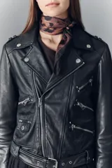 Campera negra de cuero ovino, estilo rocker, con cinturón, charreteras y solapas. Tiene cierres y detalles metálicos en frente y espalda.