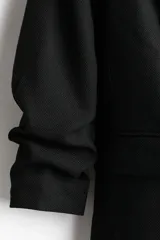 Blazer negro entallado confeccionado en mezcla de viscosa, con hombreras, solapas de muesca, mangas tres cuartos fruncidas y bolsillos delanteros con solapa. Sin cierre.