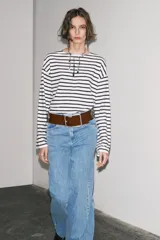 Camiseta de manga larga a rayas horizontales blancas y negras, con cuello redondo y bajo con aberturas laterales.