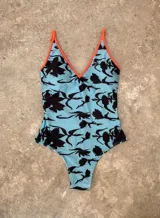 Malla entera de lycra estampada con diseño abstracto en tonos blanco, negro, amarillo y violeta. Tiene escote en V y tirantes finos.