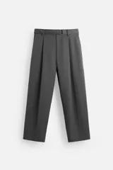 Pantalón negro de corte ancho con cinturón de tela con hebilla metálica y pliegues frontales.