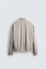 Cazadora bomber color azul marino de tejido técnico ligero, con cuello solapa y manga larga. Cuenta con bolsillos de vivo en la cadera, bolsillo interior, acabados en rib y cierre frontal con cremallera.