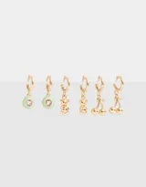 Set de tres pares de aros dorados tipo argolla con dijes colgantes: círculos verde pastel con corazón rosa, ositos y cerezas.