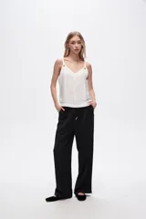 Pantalón negro de rayon, corte amplio, tiro alto y bolsillos laterales.