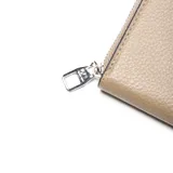 Fichero o billetera pequeña con cierre perimetral, color beige claro, con textura de cuero y logo metálico plateado con las letras "XL" en el frente.