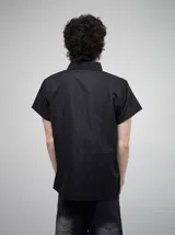 Camisa negra de manga corta con cuello, corte regular fit y estampado gráfico en blanco con tipografía gótica y un diseño central.