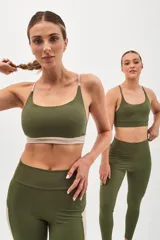 Top deportivo color beige con banda inferior azul y tirantes finos azul marino. Espalda cruzada con doble tira.