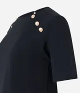 Blusa negra de crepé con cuello redondo, mangas cortas y botones decorativos dorados en los hombros.