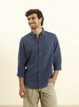 Camisa azul marino de lino y algodón, con cuello abotonado, manga larga con puños enrollados, bolsillo de parche en el pecho y cierre frontal con botones.