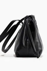 Cartera bandolera negra de tejido revestido con diseño alargado y asas largas. Ajuste con cordón y cierre magnético oculto.