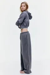 Pantalón de jogging gris de corte holgado, con cintura elástica ajustable con cordón, bolsillos laterales y piernas anchas.