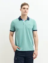 Remera polo blanca de piqué con cuello y puños en azul marino. Tiene tapeta de dos botones y bolsillo de parche en el pecho.