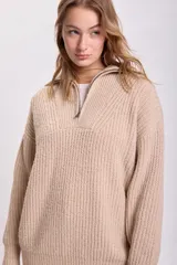 Sweater beige de punto grueso, con cuello polo y cierre metálico parcial.