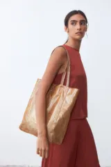 Bolso tipo shopper color dorado con textura brillante.