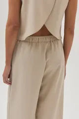 Pantalón de vestir color beige, de corte ancho y tiro alto, con cintura elástica ajustable con cordón.