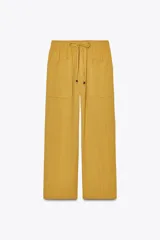 Pantalón mostaza de tiro alto con cintura elástica ajustable con cordón, bolsillos de plastrón en delantero y espalda, y pernera recta.