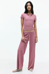 Pantalón recto color rosado, de punto con efecto arrugado, con elástico y cordón ajustable en la cintura.
