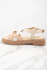 Sandalias con plataforma color beige y suela marrón. Tiras cruzadas en cuero color beige con textura y cuero plateado brillante.