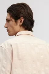 Camisa de manga corta color rosa claro, con cuello inglés, tapeta lisa, bolsillo superior abierto, canesú en la espalda y bajo recto.