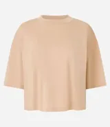 Blusa color beige, cropped y de corte amplio, confeccionada en tejido de media malla, con cuello redondo y mangas cortas.
