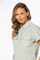 Camisa de lino color verde agua, de corte recto, con cuello camisero, medio abotonada, manga corta y dos bolsillos de parche en el pecho.