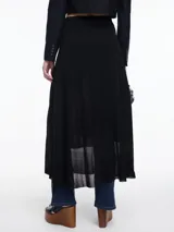 Falda larga evasé de punto con lurex, color negro. Confeccionada en tejido liviano con sutil brillo, tiene un corte evasé que acompaña el movimiento del cuerpo. Su diseño minimalista y su silueta fluida la convierten en una prenda versátil. Cintura plana y terminación ligeramente transparente en el ruedo.