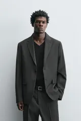 Blazer regular fit color gris oscuro con diseño de cuadros, confeccionada en tejido con lana. Tiene cuello con solapas de muesca, manga larga con puños abotonados, bolsillo de vivo en el pecho, bolsillos de solapa en la cadera, bolsillo interior, aberturas en la espalda y cierre frontal con botones.