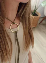 Gargantilla verde con dije circular dorado, confeccionada en bronce y cuero sintético.