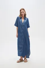 Vestido largo camisero de lyocell azul denim, corte holgado, con cuello camisero, mangas cortas con dobladillo y cierre frontal con botones.
