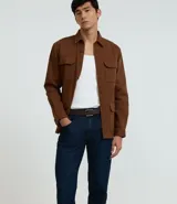 Pantalón slim fit confeccionado en tejido denim azul oscuro, con cintura con trabillas, cierre tradicional y bolsillos.